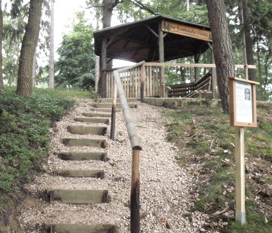 Eine Holzhütte im Wald, erreichbar über eine steinige Treppe. Ein Schild informiert über die Clemens-de-lassaulx-Hütte., © VG Adenau,petermenches Eine Holzhütte im Wald, erreichbar über eine steinige Treppe. Ein Schild informiert über die Clemens-de-lassaulx-Hütte., © VG Adenau,petermenches