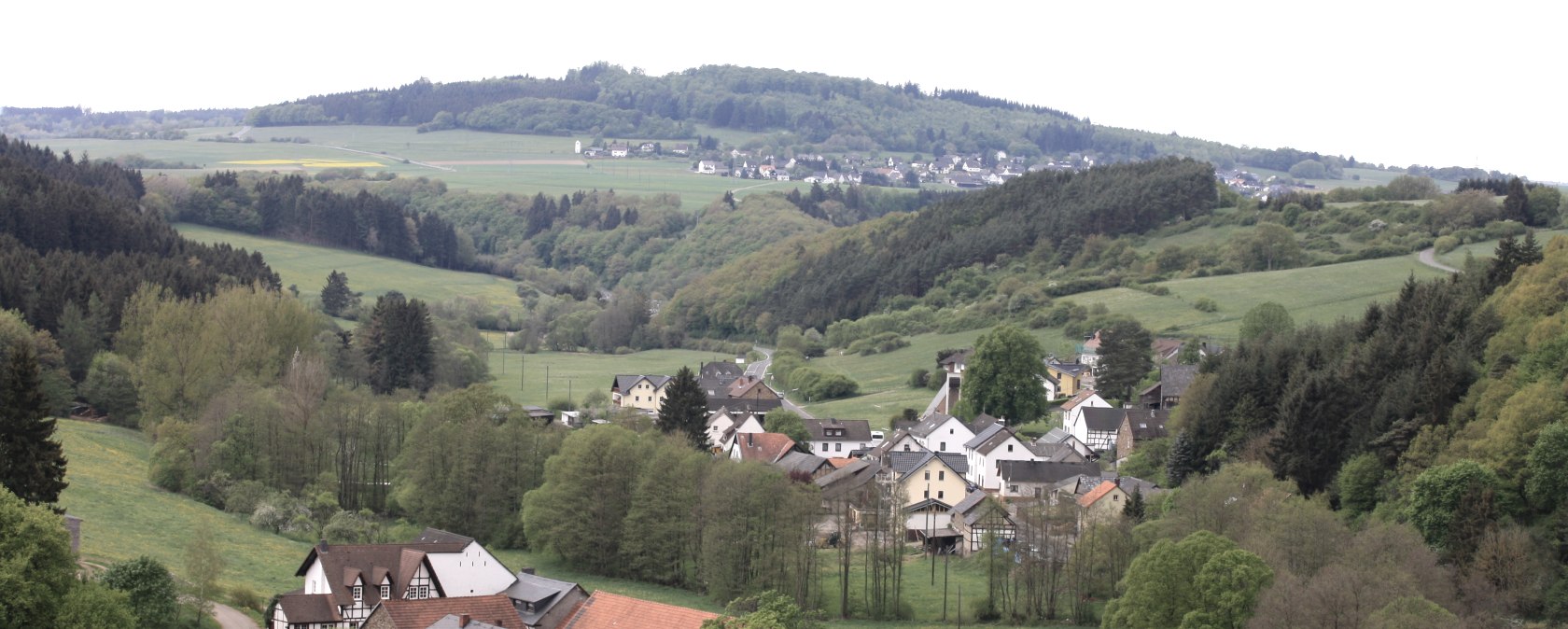 Dorf Wirft in grüner Hügellandschaft, umgeben von Wäldern und Feldern, unter bewölktem Himmel., © Walter Schmitz Dorf Wirft in grüner Hügellandschaft, umgeben von Wäldern und Feldern, unter bewölktem Himmel., © Walter Schmitz