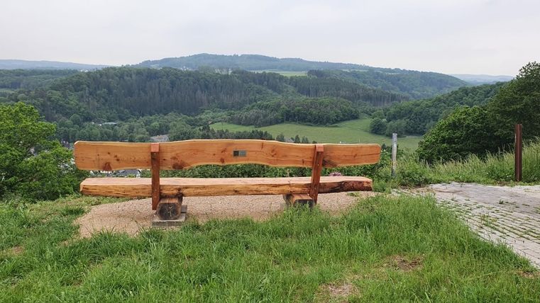 Eine große Holzsitzbank von hinten fotografiert mit Blick auf 