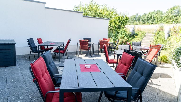 Een gezellige terras met verschillende zitplaatsen en een tafel. De omgeving is groen en uitnodigend.