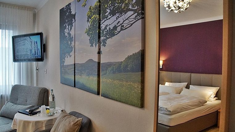 Une chambre moderne avec un lit confortable et un mobilier élégant. Un tableau de paysage coloré est accroché au mur.