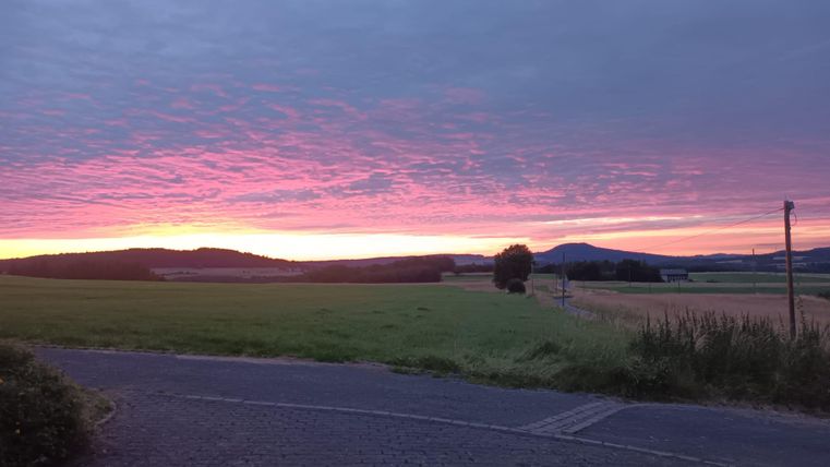 A picturesque sunset over a vast landscape. The sky glows in soft shades of purple and pink.