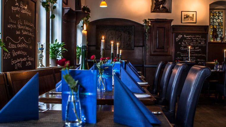 A cozy restaurant with a beautifully set table. Blue napkins and fresh roses create an inviting atmosphere.