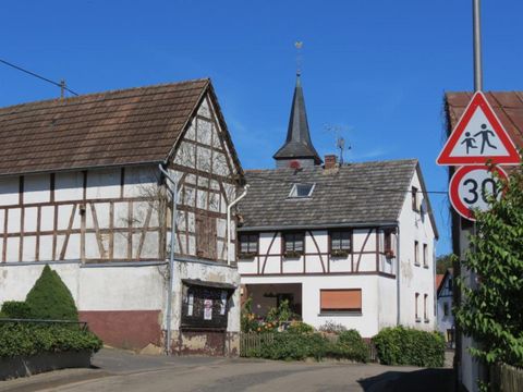 Ein malerisches Dorf mit Fachwerkhäusern und einem Kirchturm. Die Straße ist durch ein Verkehrsschild mit der Geschwindigkeitsbegrenzung von 30 km/h gekennzeichnet.