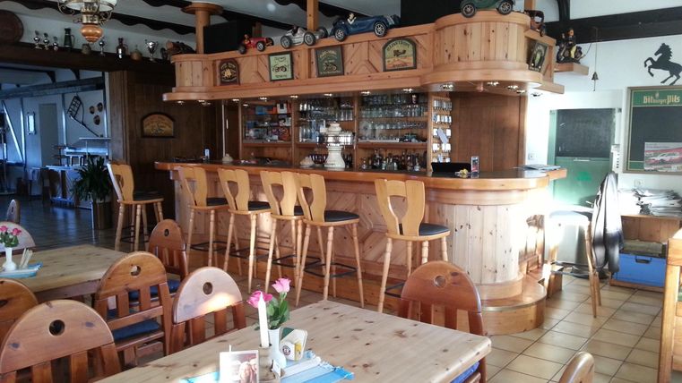 Eine gemütliche Bar mit Holzregalen und Stühlen. Der Raum ist hell und einladend, ideal für gesellige Treffen.