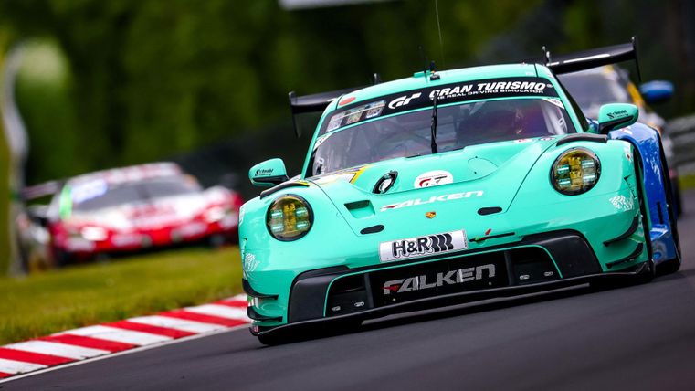 Ein Rennwagen in leuchtendem Türkis fährt schnell auf einer Rennstrecke. Im Hintergrund ist ein weiterer Rennwagen zu sehen.