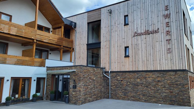 Ein modernes Landhotel mit Holzfassade und großen Fenstern. Der Eingangsbereich ist freundlich gestaltet und lädt zum Verweilen ein.