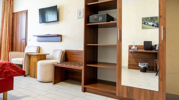 Een moderne kamer met houten planken en een grote spiegel. Op de achtergrond is er een bureau en gezellige zitplaatsen.