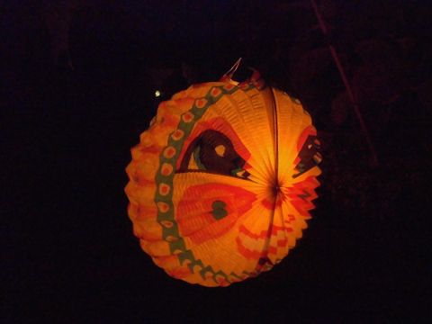 Eine bunte Laterne in Form eines Schmetterlings leuchtet sanft im Dunkeln. Sie hat lebhafte Farben und ein dekoratives Design.