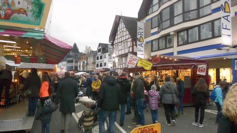 Eine belebte Straße mit vielen Menschen und Ständen. Die Architektur der Gebäude im Hintergrund ist typisch für eine deutsche Stadt.