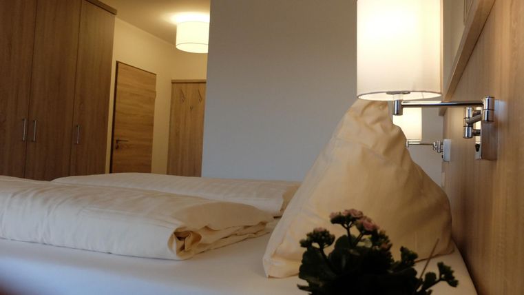 Een gezellige slaapkamer met een groot bed en een moderne lamp. Een kleine bloempot staat op het nachttafeltje.