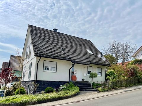 A modern house with a gable roof and a well-kept front garden. The surroundings are green and pleasantly designed.