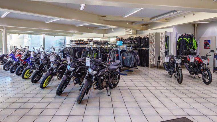 Ein Motorradgeschäft mit einer Vielzahl von Motorrädern und Motorradzubehör. Die Ausstellungsfläche ist hell und einladend.