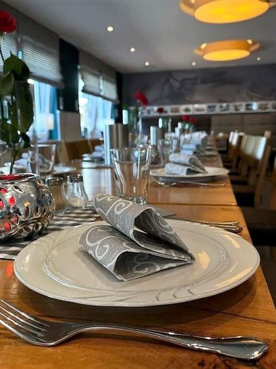 An elegantly set table with white plates and decorative napkins. On the table, there are flowers and glasses for a stylish ambiance.