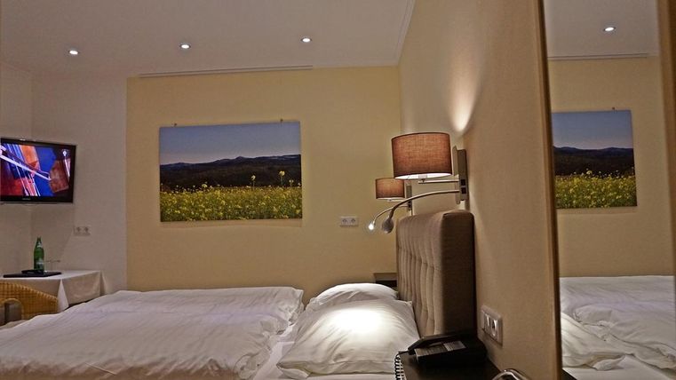 Une chambre d'hôtel confortable avec deux lits et un équipement moderne. Des paysages sont accrochés au mur, et une télévision est également présente.