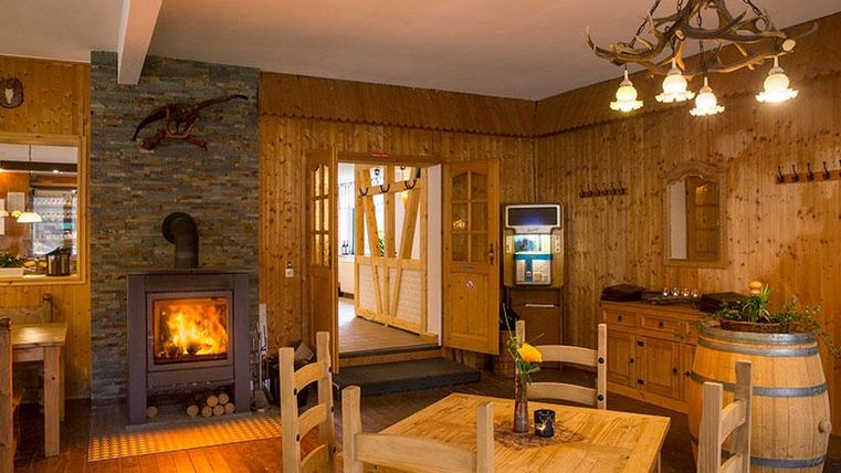 A cozy room with wooden walls and a fireplace. There is a table with chairs and rustic decor elements.