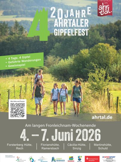 Das Bild zeigt eine Gruppe von vier Wandern auf einem malerischen Weg in einer grünen Landschaft. Im Hintergrund sind sanfte Hügel und ein klarer Himmel zu sehen.