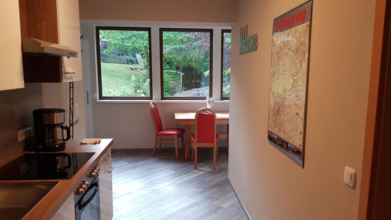 Een moderne keuken met een eetgedeelte en grote ramen die uitkijken op een groene tuin. De ruimte is helder en uitnodigend ingericht.