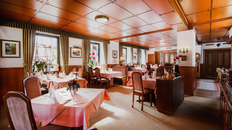 Een uitnodigend restaurant met aangenaam gedecoreerde tafels en warm houten ontwerp. Grote ramen zorgen voor licht en een gezellige sfeer.