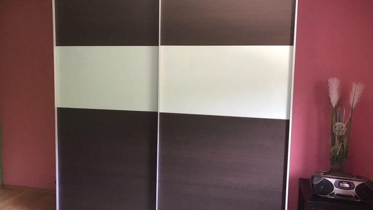 A modern room divider made of wood with a transparent strip. The wall is in soft colors and offers a minimalist look.