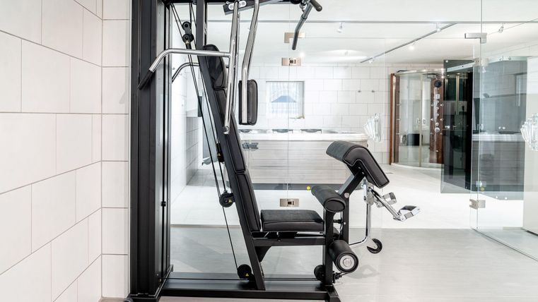 Een modern fitnessapparaat staat in een elegante ruimte met lichte tegels. Het gebied ziet er helder en uitnodigend uit, ideaal voor een workout.