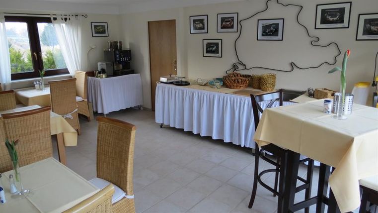 Un restaurant confortable avec des tables et des chaises en rotin. Des images sont accrochées aux murs, et une table de buffet est préparée pour les invités.