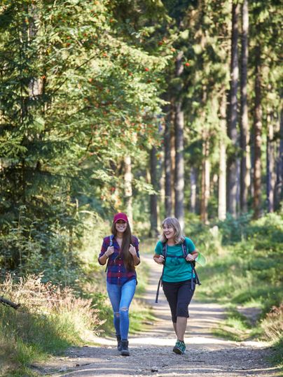 Zwei Frauen wandern auf einem Waldweg in der Hocheifel.