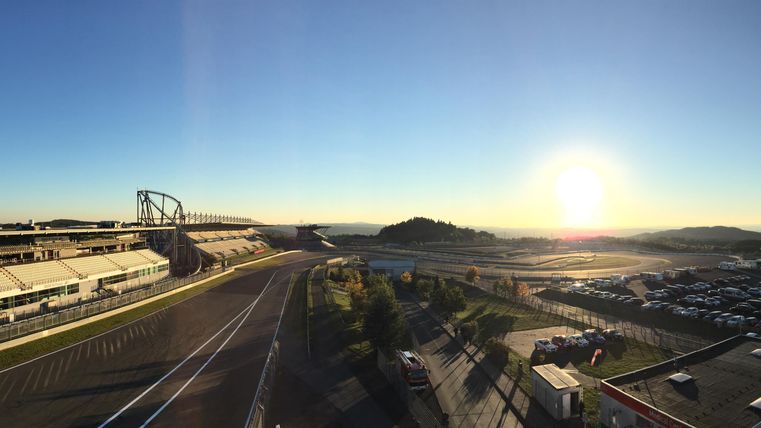 Eine Panoramasicht auf eine Rennstrecke bei Sonnenaufgang. Die Landschaft ist ruhig und der Himmel ist klar.