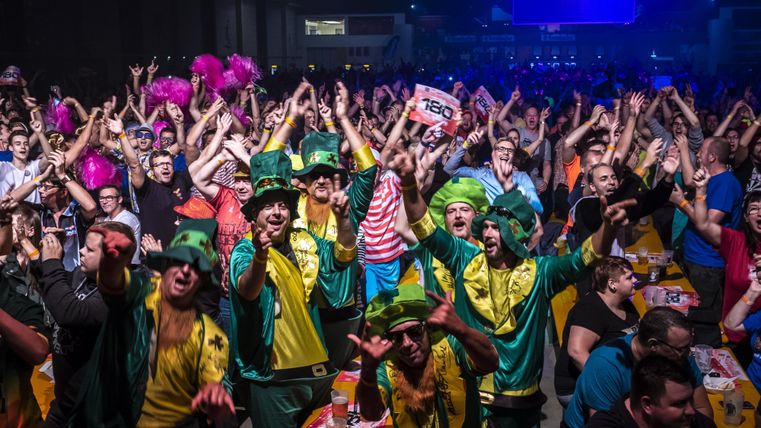 Eine lebhafte Party mit vielen fröhlichen Menschen in bunten Kostümen. Die Menge jubelt und zeigt Begeisterung.