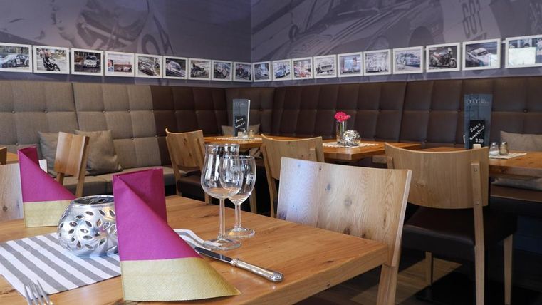 A cozy restaurant with wooden chairs and tables.
On the tables, there are pink and gold tablecloths as well as glasses and decorative elements.