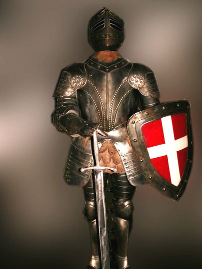 Ritterrüstung mit Schwert und Schild mit weißem Kreuz auf rotem Grund.
