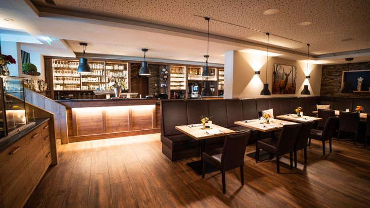 A modern restaurant with wooden flooring and stylish furnishings. The inviting atmosphere is enhanced by soft lighting and decorated tables.