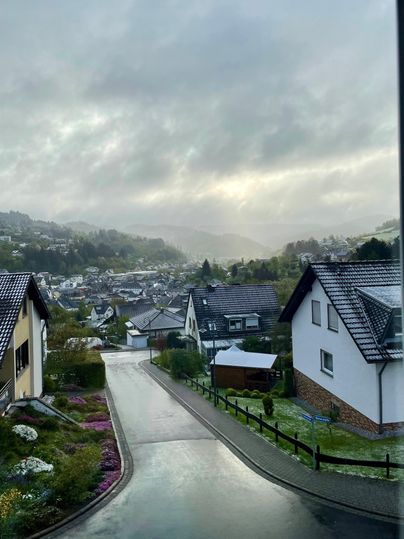 A picturesque view of a small village in the fog. The road gently descends between cozy houses.