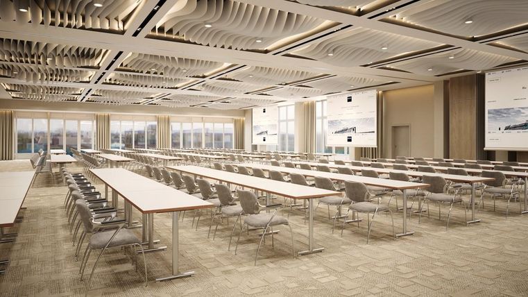 A modern conference room with long tables and several chairs. Large windows provide plenty of daylight.