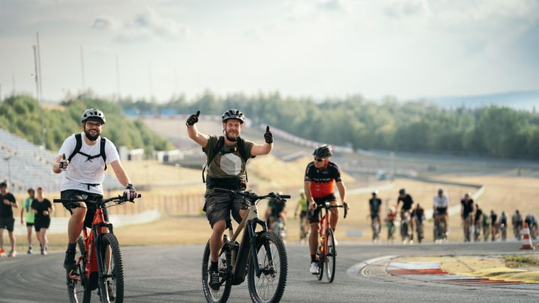 A group of cyclists is cheerfully riding on a racetrack. The atmosphere is lively and sporty.