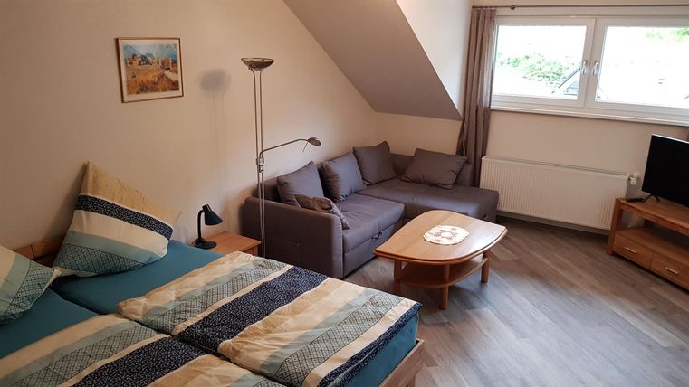 Een gezellige kamer met twee bedden en een zitgedeelte. De kamer heeft grote ramen en moderne meubels.