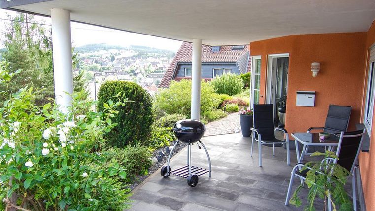 A beautiful outdoor area with a grill and modern garden furniture. The surroundings are green and inviting, perfect for relaxing.