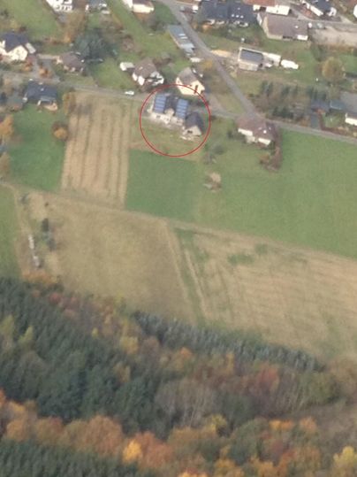 Aerial view of rural areas with a large residential house in the center. Surrounded by fields and forests, the landscape displays beautiful autumn colors.