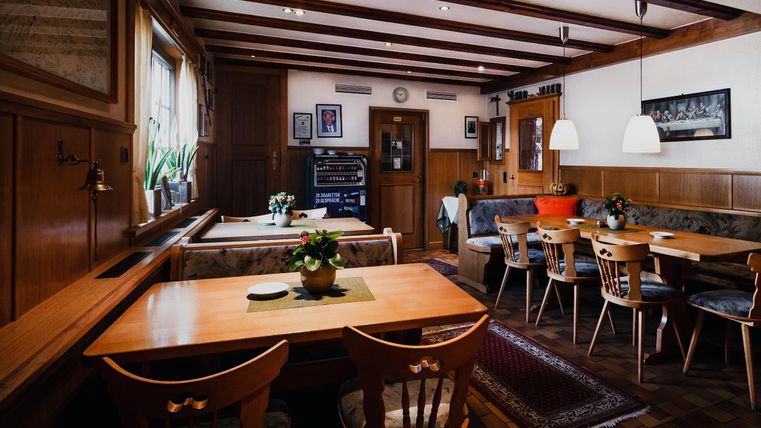 Een gezellige restaurant met houten bekleding en tafels. Er zijn planten op de tafels en een uitnodigende sfeer.