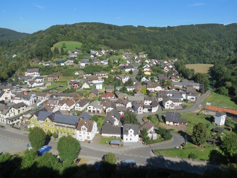Ein malerisches Dorf in einer grünen Hügellandschaft. Die Häuser sind bunt und gut angeordnet, umgeben von Natur.
