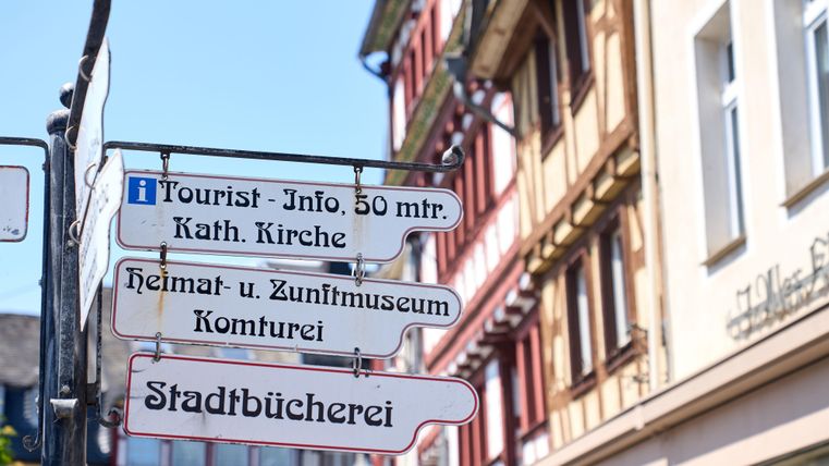 A city mixed sign with directional signs to various attractions. The buildings in the background showcase charming, historic architecture.