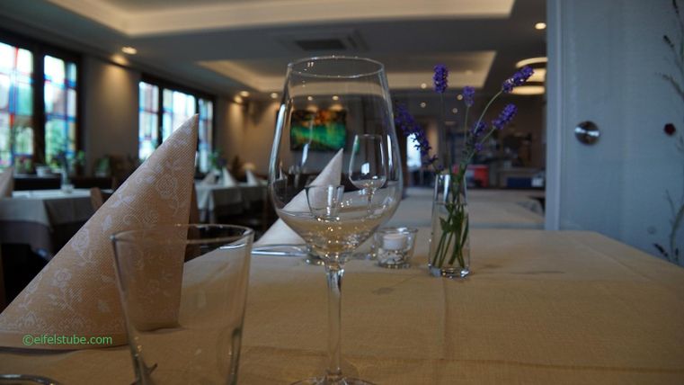 Une table élégante dans un restaurant avec des verres et des fleurs de lavande. L'ambiance est chaleureuse et accueillante.