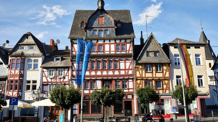 Fachwerkhäuser in Adenau mit Europaflagge und Deutschlandflagge.