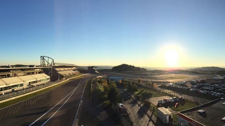 Eine Panoramaaufnahme einer Rennstrecke bei Sonnenaufgang. Im Hintergrund sind sanfte Hügel und ein klarer Himmel zu sehen.