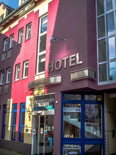 A modern hotel building with a colorful facade. The reception is located on the ground floor and is clearly visible.