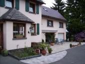 Une maison confortable avec une entrée soignée et des pots de fleurs. La cour est accueillante et offre de l'espace pour des sièges en plein air.