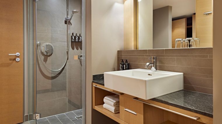 A modern bathroom with a shower and a stylish sink. The walls are bright, and there are practical storage spaces.