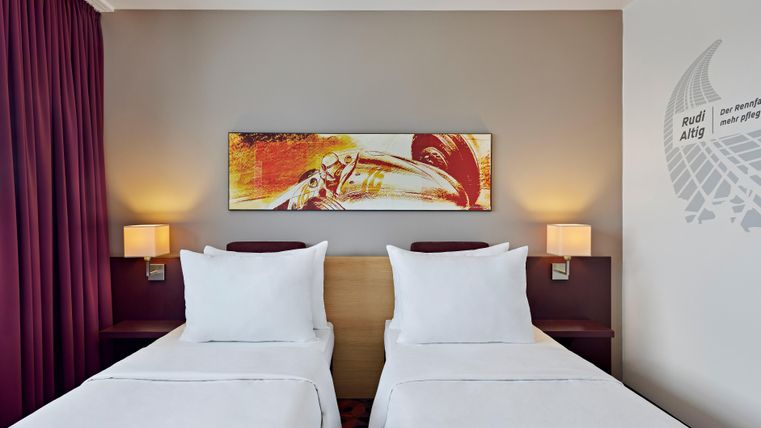 A modern hotel room with two single beds and elegant decoration. The walls are in soft colors, complemented by cozy lighting.