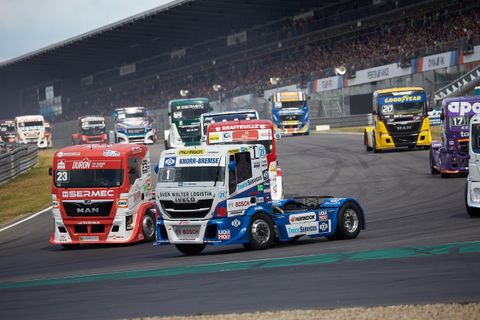 Ein spannendes Truckrennen auf einer Rennstrecke mit mehreren Fahrzeugen. Die Trucks fahren zügig in einer kurvenreichen Umgebung.