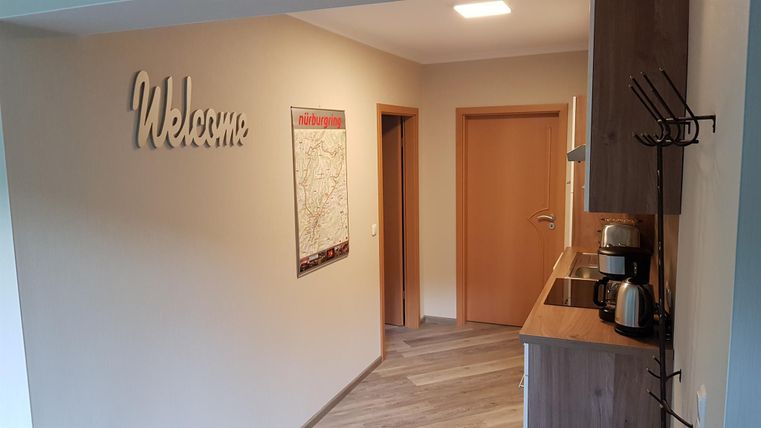 Een uitnodigende hal met een "Welcome"-bord en een kleine keuken. Aan de muur hangt een kaart.